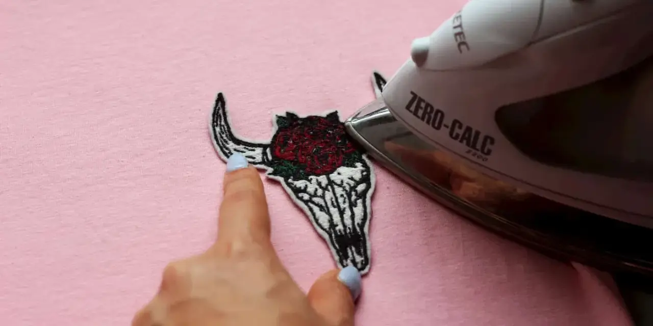 Come attaccare toppe termoadesive: un teschio di toro con rose viene stirato su una maglietta rosa.