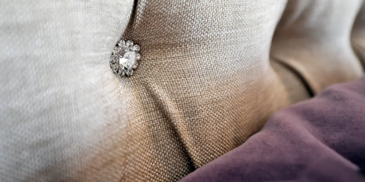 Tessuto per rivestimenti con un bottone decorativo tempestato di strass.