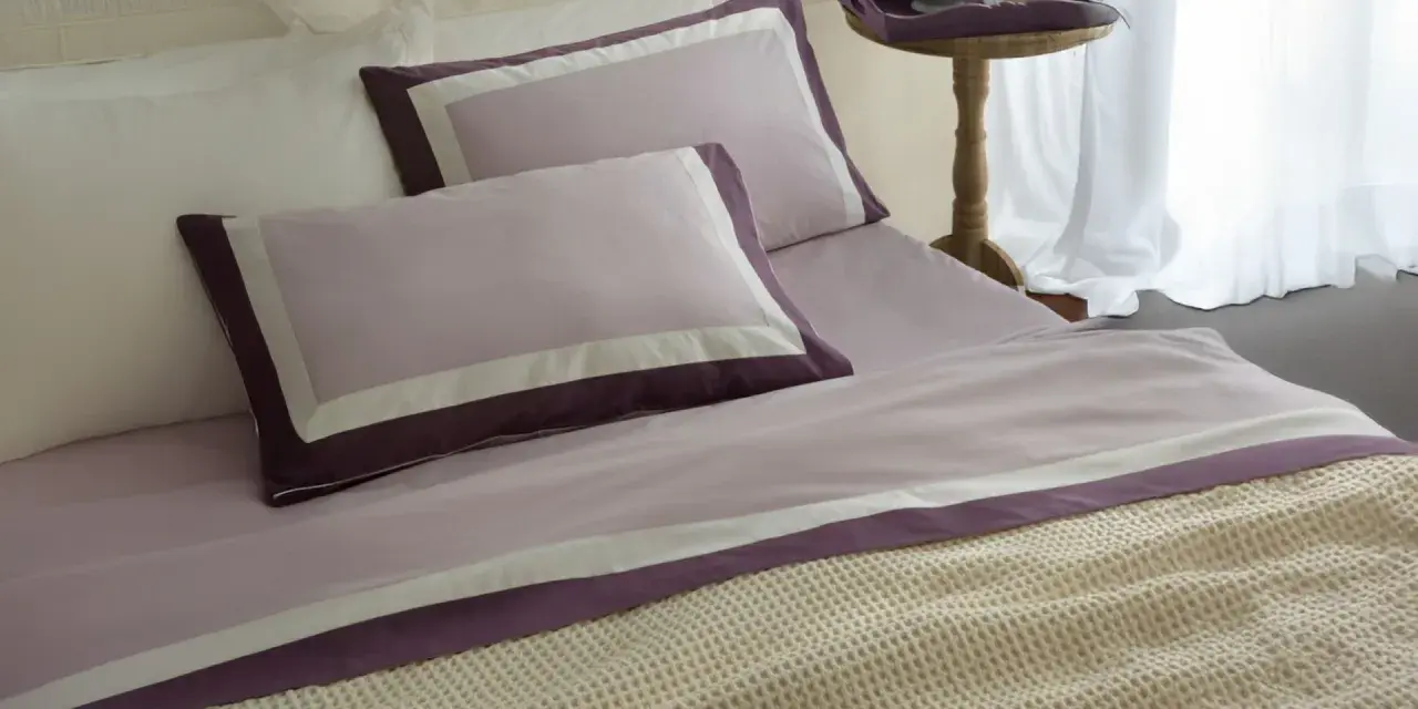 Letti preparati con lenzuola in cotone percalle si stira, con federe lilla e bordi viola.
