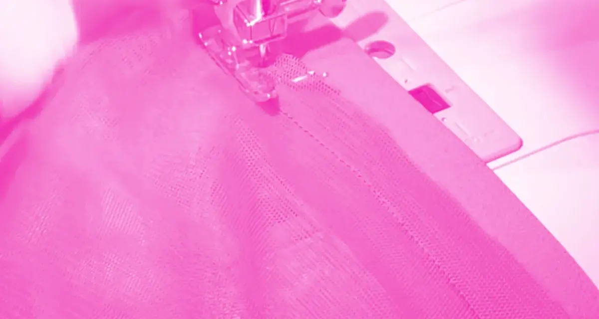 Macchina da cucire al lavoro per cucire una gonna di tulle rosa.