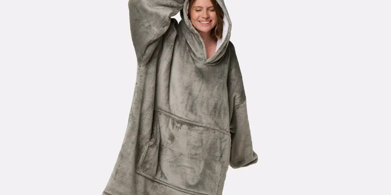 Donna sorridente indossa una felpa oversize grigia, morbida e confortevole, perfetta per chi cerca come ammorbidire tessuti rigidi e godersi il relax.