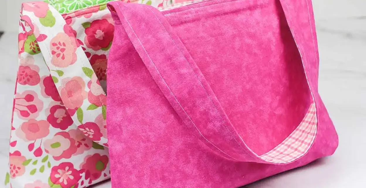 Two handmade fabric bags, one pink with a floral pattern, the other solid pink with a plaid lining.