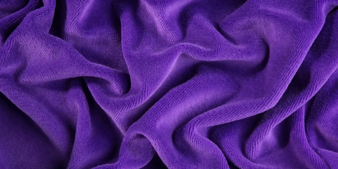 Tessuto di velluto viola drappeggiato, morbido e soffice. Scopri come lavare il velluto per mantenerlo splendente.