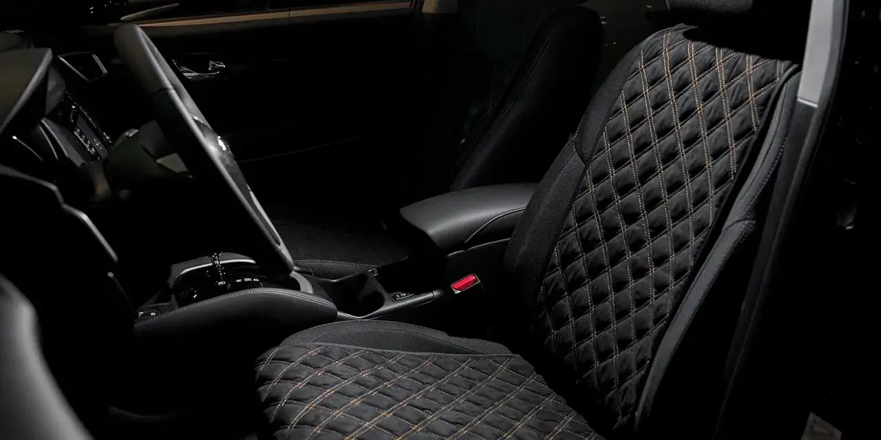 Interno auto con sedili neri trapuntati, il miglior tessuto per sedili auto per un comfort elegante.