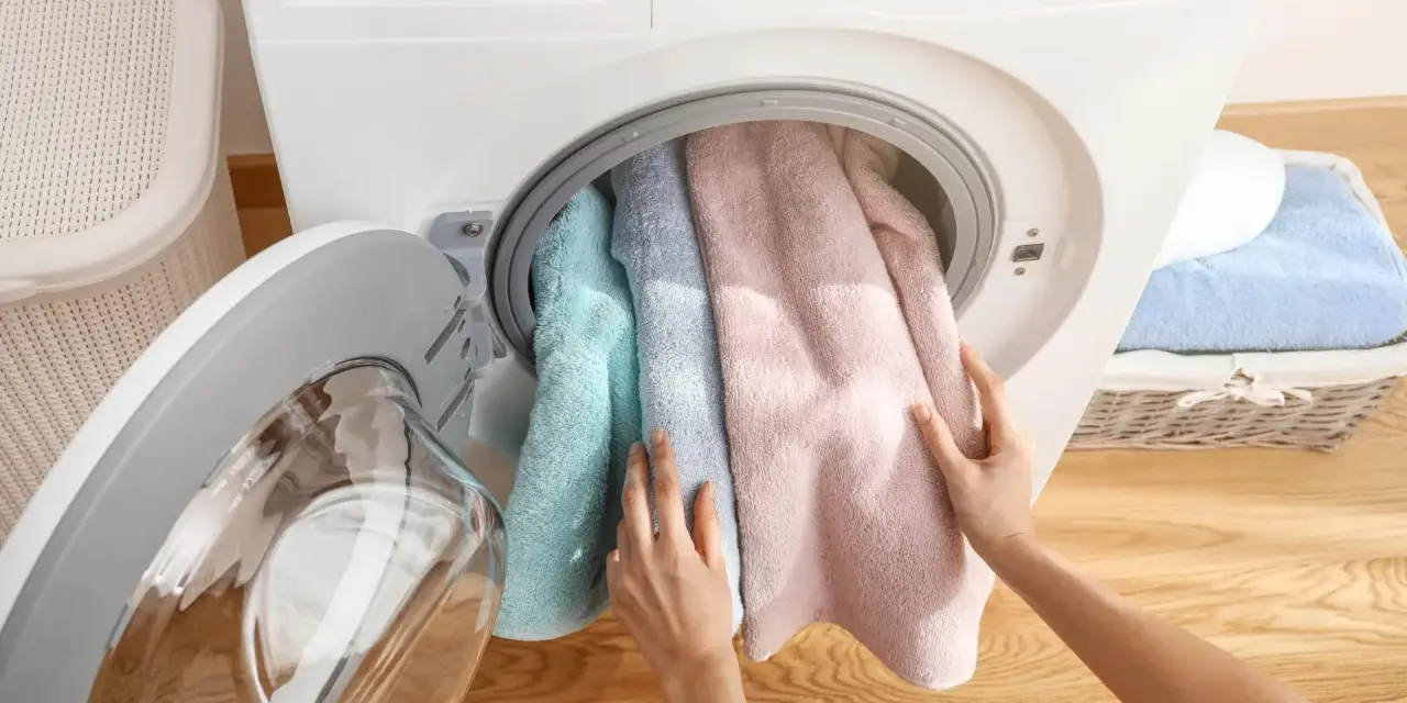 Mani inseriscono asciugamani color pastello nella centrifuga asciugamani.
