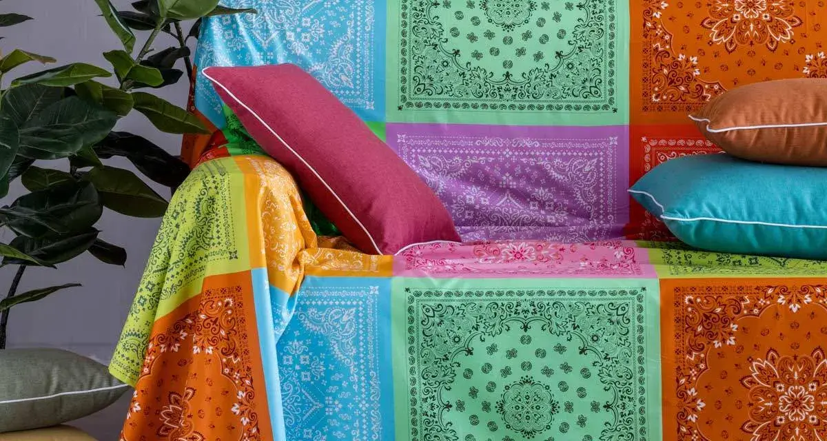 Un modo creativo per coprire una poltrona con un foulard colorato, creando un patchwork vivace.