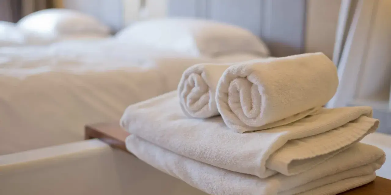 Asciugamani bianchi piegati e arrotolati, pronti per l'uso. Le misure asciugamani sono perfette per un bagno accogliente.