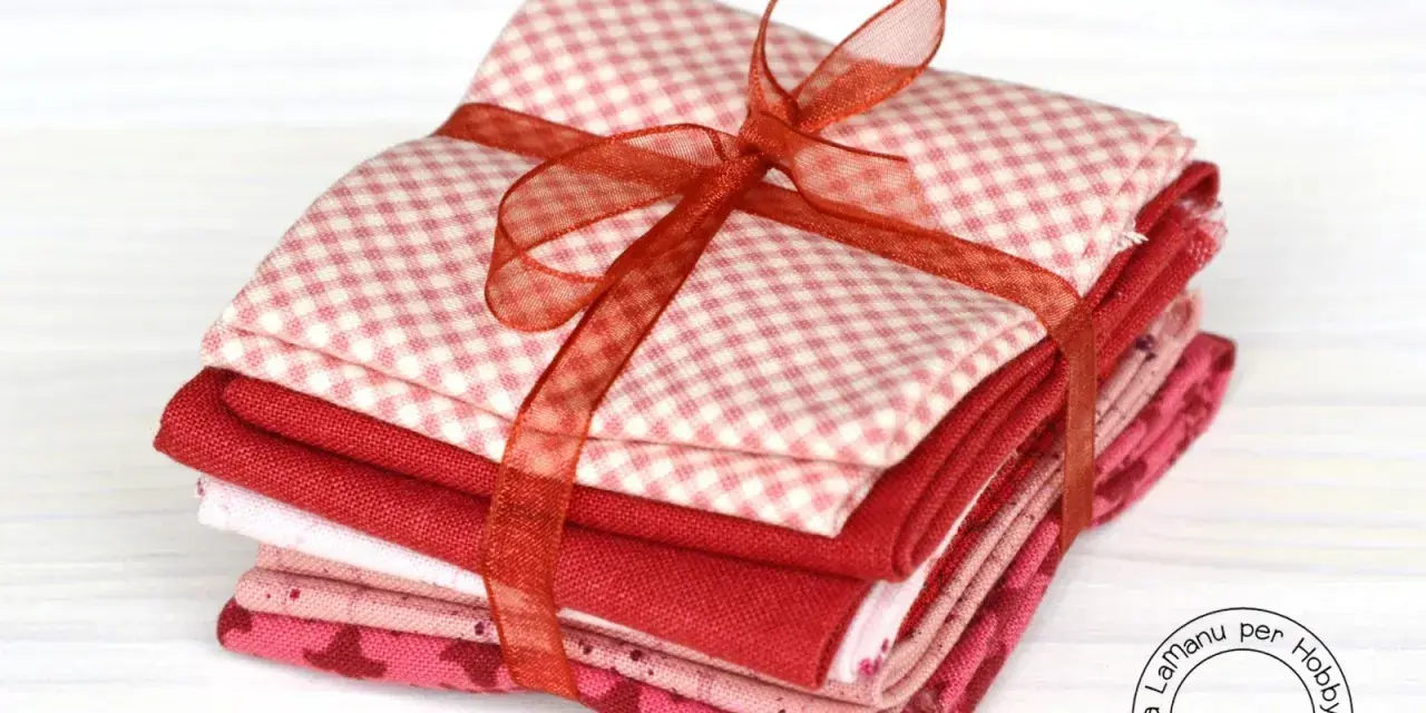 Fazzoletti di stoffa rossi e rosa, con fantasie a quadretti e cuoricini, legati da un nastro. Perfetti per un progetto di cucito creativo.