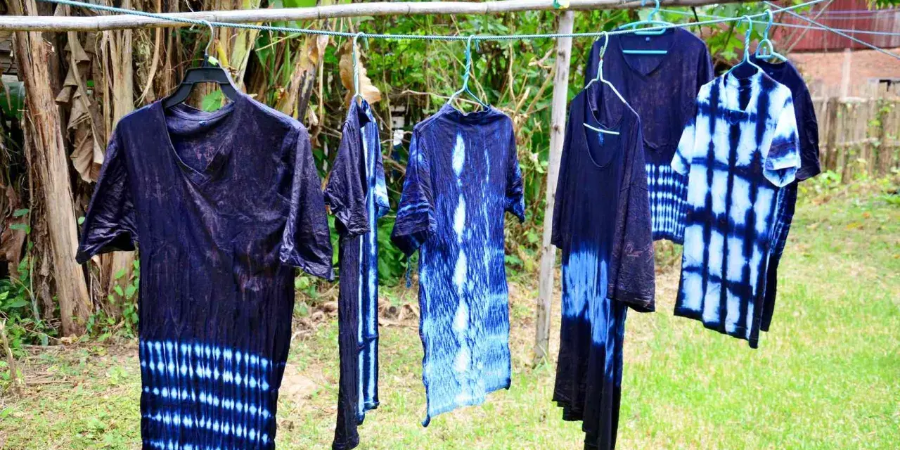 Abiti con motivi tie-dye blu e bianchi, pronti per asciugare dopo aver provato a tingere tessuti sintetici.