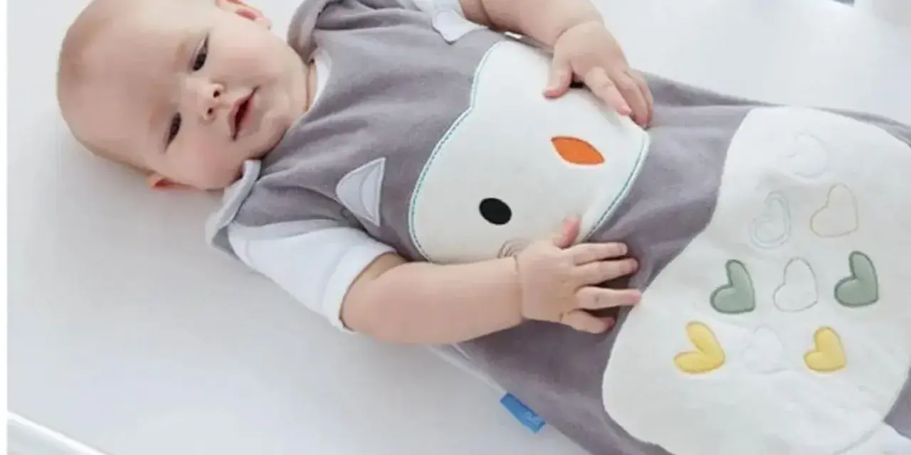 Bambino in sacco nanna con simpatico disegno di gufo. Il sacco nanna è ideale per neonati e bambini piccoli, offrendo comfort e sicurezza durante il sonno.