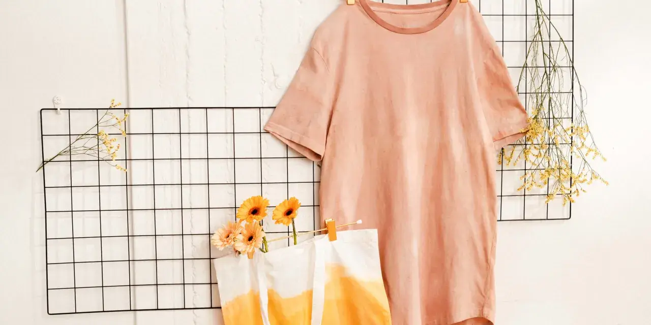 T-shirt rosa e borsa con sfumature arancioni, ispirazione per come tingere un vestito. Fiori e rametti secchi decorano.