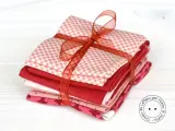 Fazzoletti di stoffa rossi e rosa, con fantasie a quadretti e cuoricini, legati da un nastro. Perfetti per un progetto di cucito creativo.