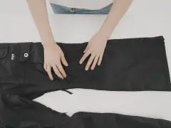 Mani che preparano un buco nei pantaloni neri per rammendare.