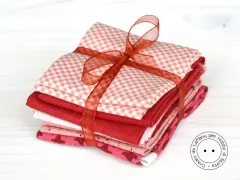 Fazzoletti di stoffa rossi e rosa, con fantasie a quadretti e cuoricini, legati da un nastro. Perfetti per un progetto di cucito creativo.