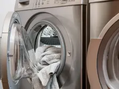 Lavatrice con un tappeto grigio all'interno, pronta per il lavaggio. Scopri come lavare i tappeti in lavatrice per mantenerli freschi e puliti.