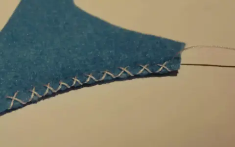Bordo di feltro blu rifinito con un punto overlock a mano.