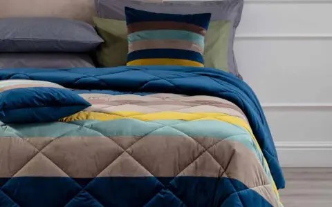 Trapunta a righe colorate, con cuscini coordinati. Perfetta per capire se è più calda la trapunta o il piumino.