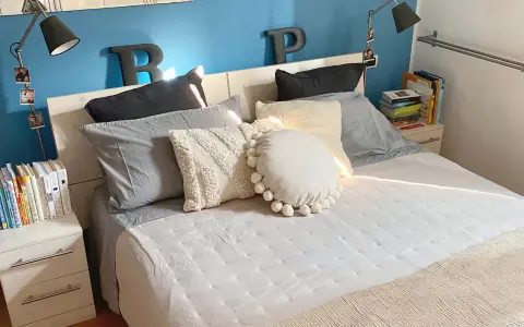 Letto con cuscini morbidi e coperta beige. Impara come fare il letto per un risveglio sereno.