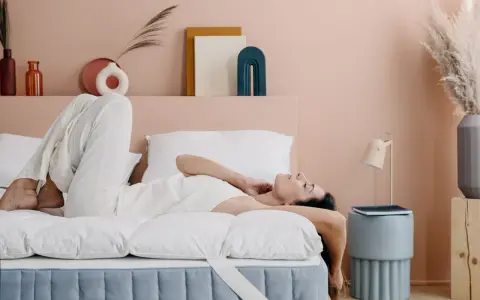 Donna rilassata su un letto con topper matrimoniale, che ne dimostra il comfort.