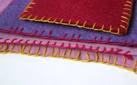 Tessuti colorati sovrapposti, rifiniti con un punto coperta giallo, rosa e rosso.