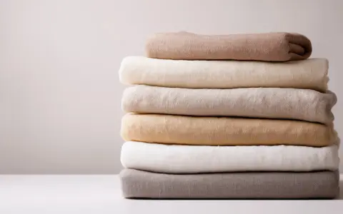 Pila di tessuti in lino colorato, pronti per essere lavati. Scopri come si lava il lino per mantenerlo morbido e fresco.