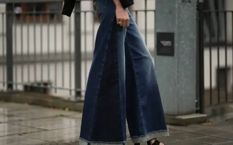 Woman wearing wide-leg denim palazzo pants with frayed hems and platform sandals.