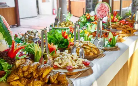 Buffet con patate arrosto, insalate fresche e frutta intagliata. Ecco come mettere la tovaglia per buffet, creando un'atmosfera invitante.