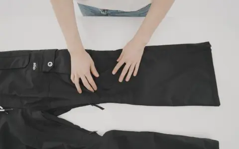 Mani che preparano un buco nei pantaloni neri per rammendare.