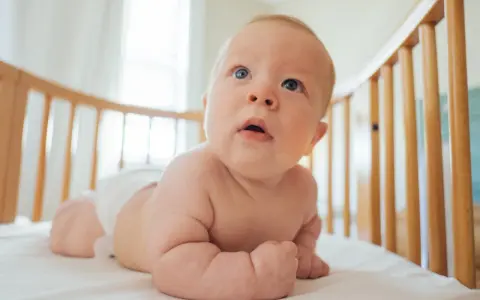 Bambino in culla, con pannolino, che esplora il mondo. Le misure lenzuolino culla sono perfette per questo piccolo esploratore.
