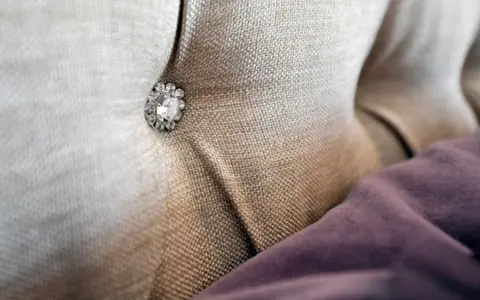 Tessuto per rivestimenti con un bottone decorativo tempestato di strass.