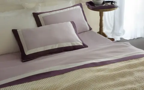 Letti preparati con lenzuola in cotone percalle si stira, con federe lilla e bordi viola.