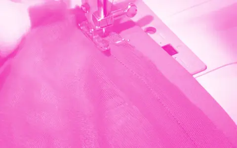 Macchina da cucire al lavoro per cucire una gonna di tulle rosa.
