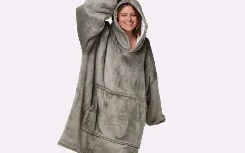 Donna sorridente indossa una felpa oversize grigia, morbida e confortevole, perfetta per chi cerca come ammorbidire tessuti rigidi e godersi il relax.