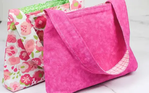 Two handmade fabric bags, one pink with a floral pattern, the other solid pink with a plaid lining.