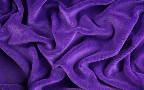 Tessuto di velluto viola drappeggiato, morbido e soffice. Scopri come lavare il velluto per mantenerlo splendente.