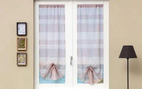 Tende a righe attaccate alla finestra, con un nodo decorativo sul fondo. Tre quadretti appesi alla parete.