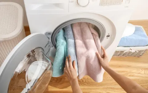 Mani inseriscono asciugamani color pastello nella centrifuga asciugamani.