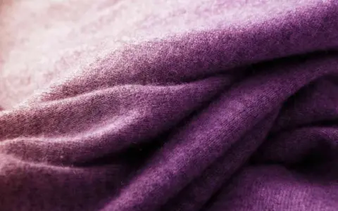 Tessuto di lana viola sfumato, ideale per imparare come tingere un maglione di lana e ottenere questo colore vibrante.