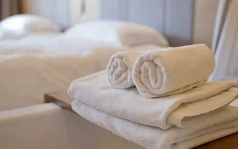 Asciugamani bianchi piegati e arrotolati, pronti per l'uso. Le misure asciugamani sono perfette per un bagno accogliente.