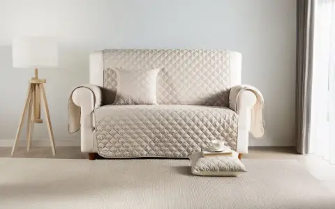 Divano con copridivano trapuntato color crema. Scopri come lavare copridivano in lavatrice per mantenerlo sempre fresco e pulito.