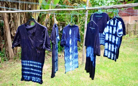 Abiti con motivi tie-dye blu e bianchi, pronti per asciugare dopo aver provato a tingere tessuti sintetici.