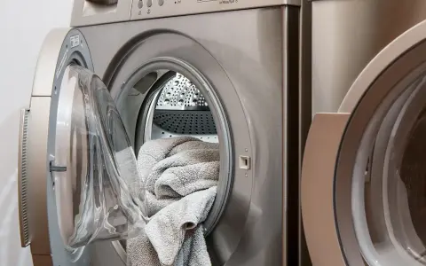 Lavatrice con un tappeto grigio all'interno, pronta per il lavaggio. Scopri come lavare i tappeti in lavatrice per mantenerli freschi e puliti.