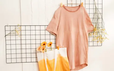 T-shirt rosa e borsa con sfumature arancioni, ispirazione per come tingere un vestito. Fiori e rametti secchi decorano.