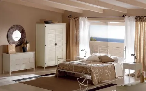 Camera da letto con letto tortora, armadio bianco e cassettiera. Abbinamenti eleganti per un ambiente rilassante con vista mare.