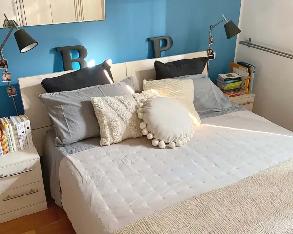 Letto con cuscini morbidi e coperta beige. Impara come fare il letto per un risveglio sereno.