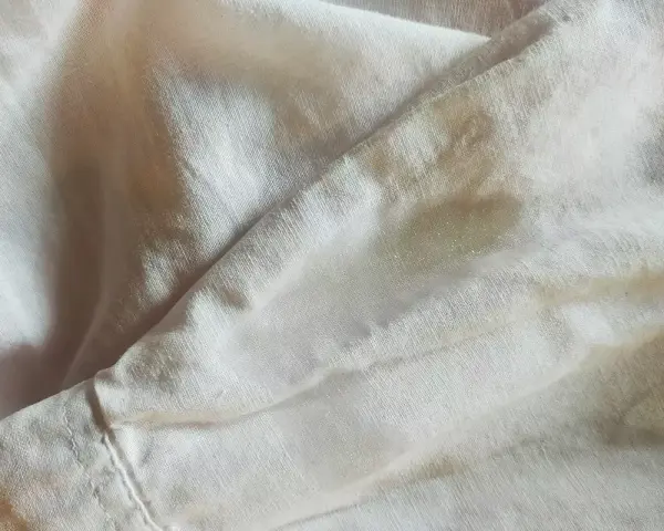 Tessuto di poliestere con macchie giallastre, forse un tentativo di smacchiare poliestere.