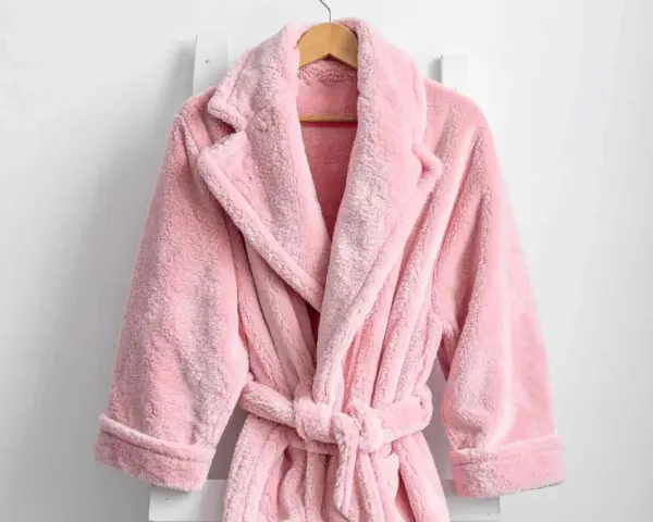 Accappatoio rosa soffice appeso. Scopri come lavare accappatoio in lavatrice per mantenerlo morbido e profumato.