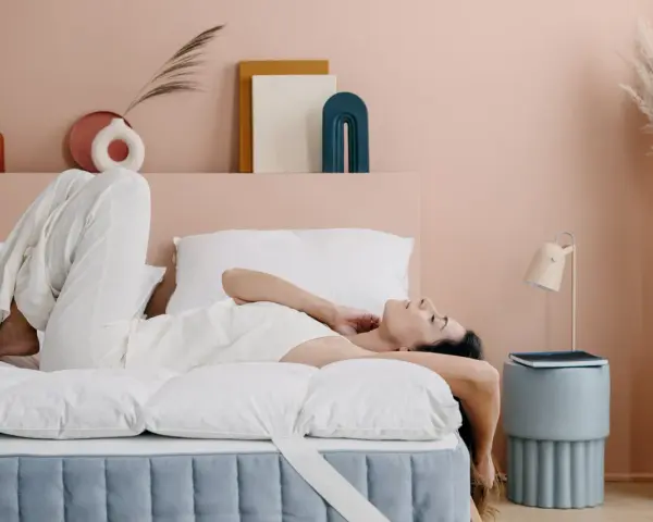 Donna rilassata su un letto con topper matrimoniale, che ne dimostra il comfort.