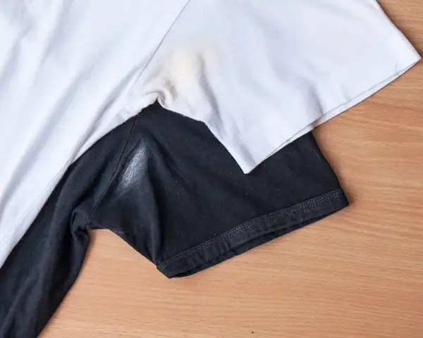 Yellow underarm stains on a white t-shirt and a white residue on a black t-shirt.
