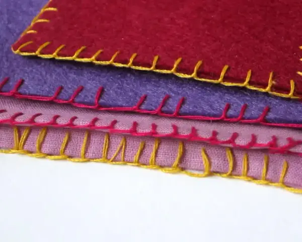 Tessuti colorati sovrapposti, rifiniti con un punto coperta giallo, rosa e rosso.